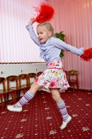 Девочка с пампушками в руках учится красиво двигаться.