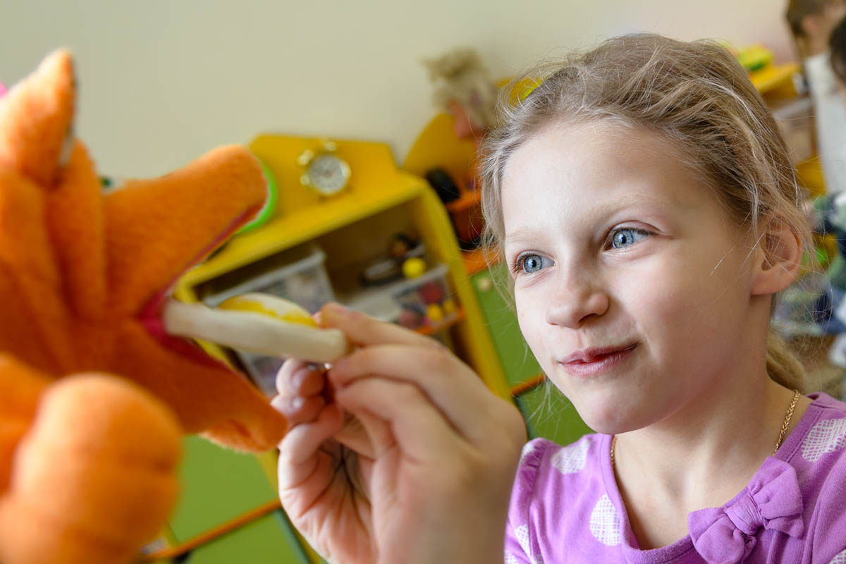 Игрушка в руках фотографа. Ребенок взаимодействует с игрушечной лисой как с живым существом.