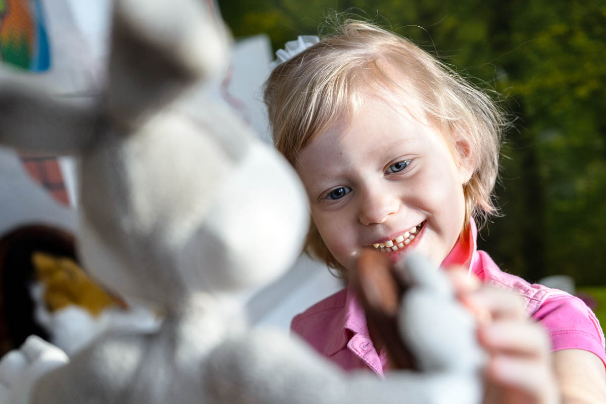 Игрушка в руках фотографа. Ребенок взаимодействует с игрушечным зайцем как с живым существом.
